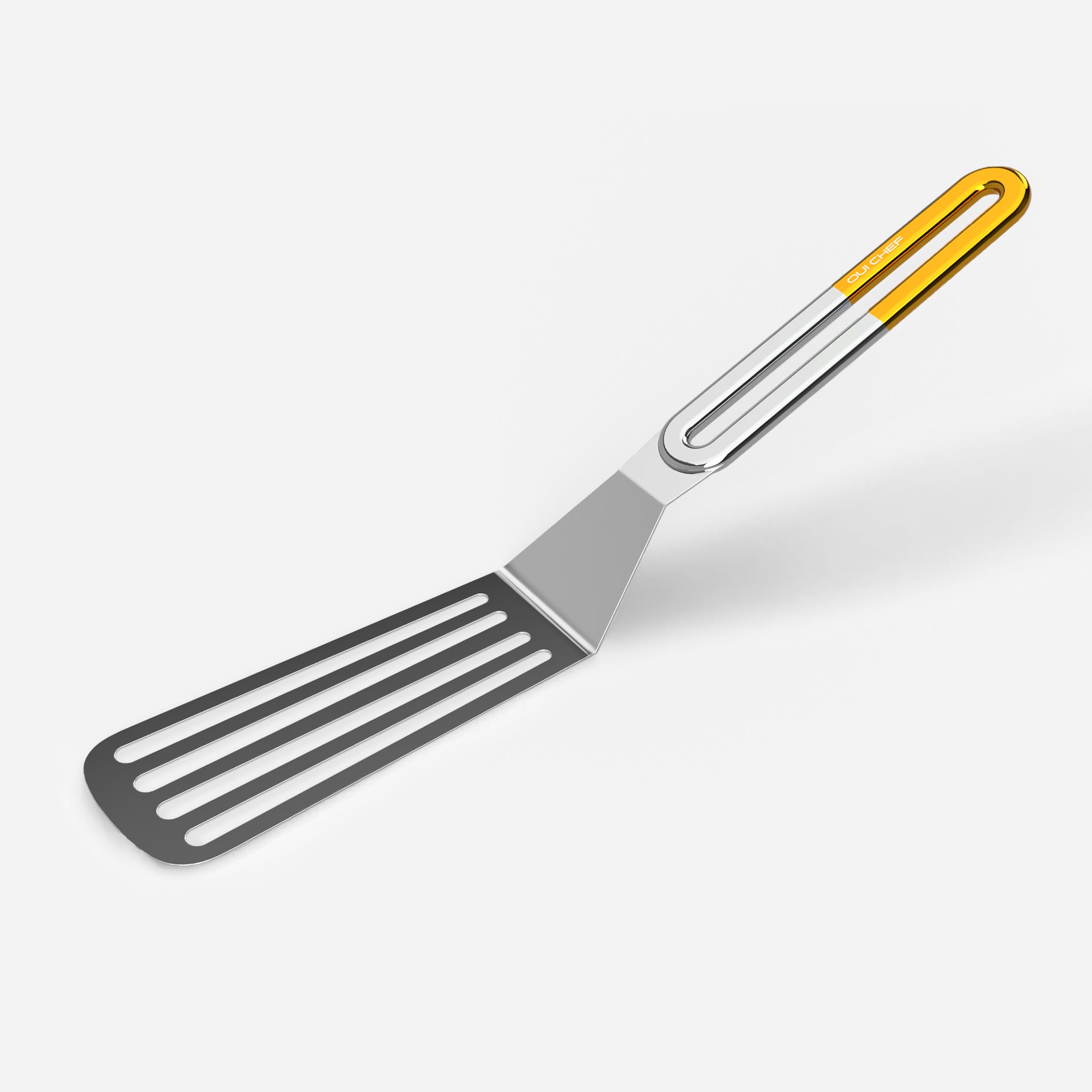 A stainless steel slotted spatula with a gold coloured handle against a white background.