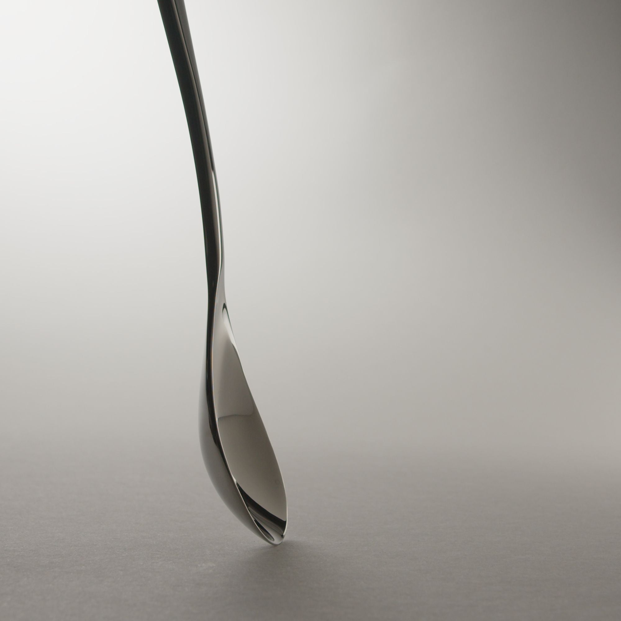 Chrome Rocher spoon standing on a light grey background.