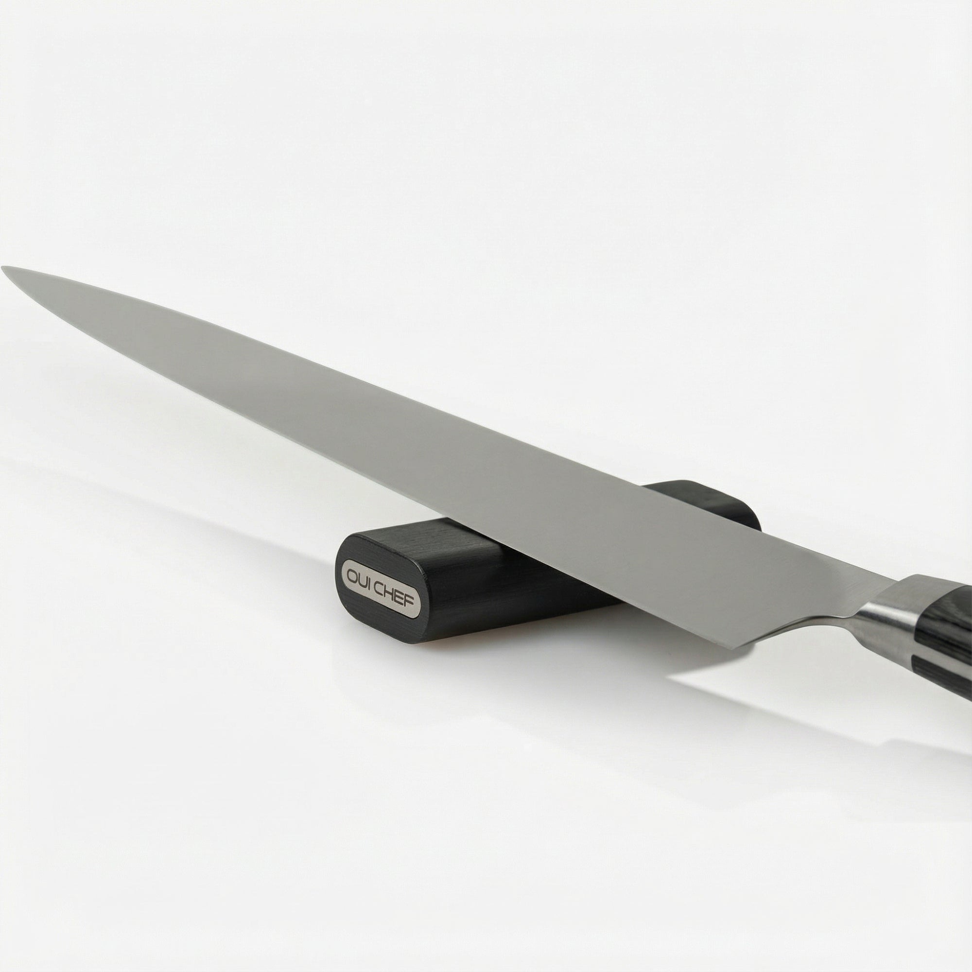 Modular laylow knife rest sitting on a kitchen neutral countertop with a chefs knife resting on it.